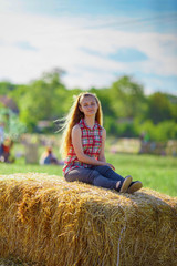 beautiful girl sits on a haystack