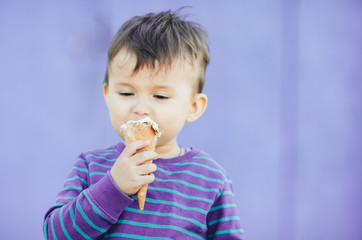 baby outdoor, on purple background eating ice cream