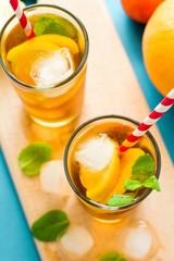Glasses of iced tea with lemon slices and mint on turquoise wooden background
