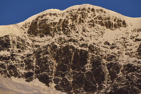 Snow covered mountain in sun light with blue sky