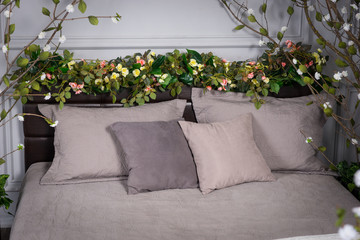 Gray cozy bedroom with flowers on the bedstead