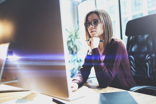 Attractive young businesswoman using desktop computer at modern working place at office.Blurred background.Horizontal.