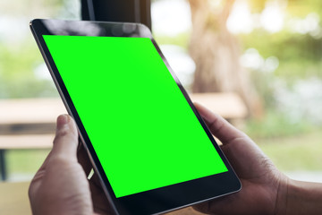 Mock up image of hands holding black tablet pc with white blank screen and