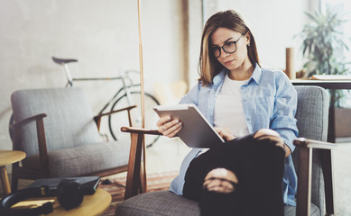 Young beautiful hipster woman browsing with touch screen device at modern coworking work place.