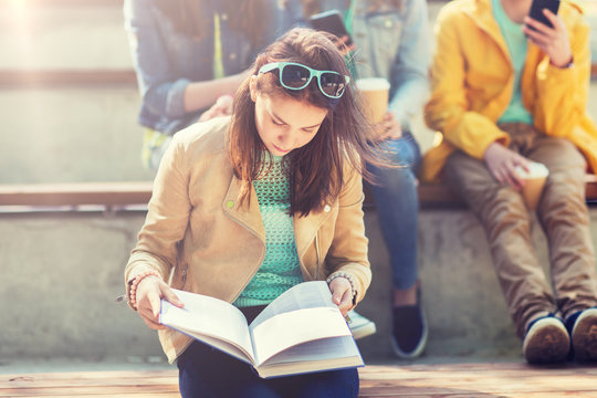 Education, High School And People Concept - High School Student Girl Reading Book Outdoors