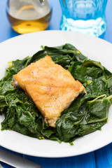 fried cod fish with greens on white plate