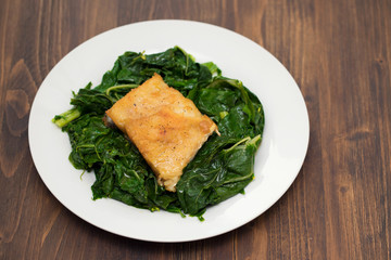fried cod fish with greens on white plate
