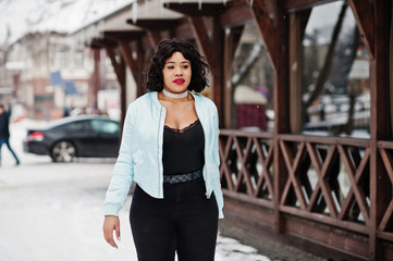 Fototapeta premium Stylish african american plus size model against wooden cafe at winter day.
