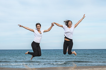 Two girls jumping on the beach