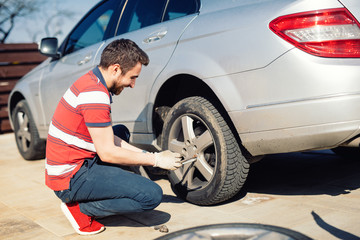 Fototapeta na wymiar Automobile problems - man chaning tires, seasonal summer tires