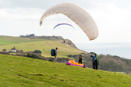 Paragliding. Ringstead Bay, Dorset / England. 02/15/2018. Paragliding pilots riding the wind off the cliffs of the Dorset Coast in training for the British Open Competitions in July. 