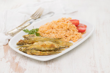fried smelts with tomato rice on white dish