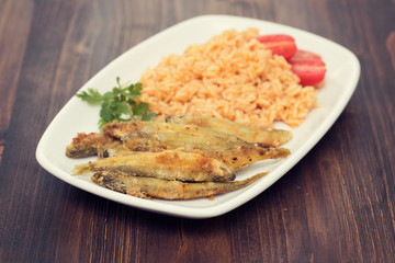 fried smelts with tomato rice on white dish