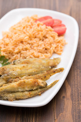 fried smelts with tomato rice on white dish
