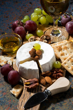 snacks and camembert cheese on a dark background, vertical