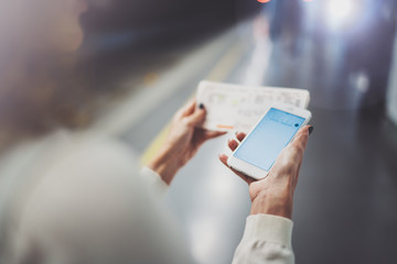 Closeup view of woman on transit platform using smartphone for make photo of train ticket while waiting rail train on metro station.