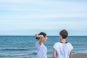Girls smiling on the beach and pulling their hair back with a normal attitude.