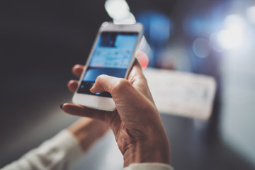 Closeup view of girl on transit platform using smartphone for make photo of train ticket while waiting rail train on metro station.