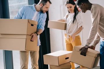 young multiethnic people carrying cardboard boxes during relocation