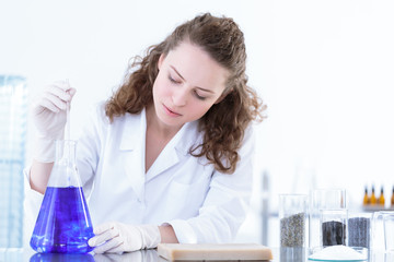 Chemist woman mixing blue solution