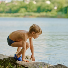 Young cute schoolboy playing near like on weekend. square aspect ratio