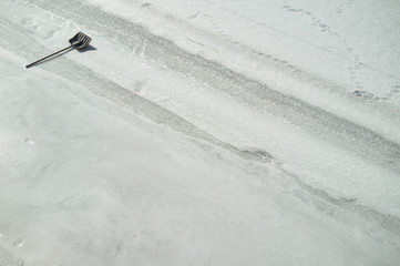 Shovel for snow cleaning is on a frozen river on a sunny spring day.