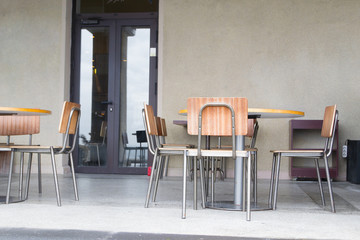 интерьер в кафе, деревянные стулья на фоне серой стены.