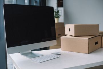 desktop computer with blank screen and cardboard boxes at workplace during relocation