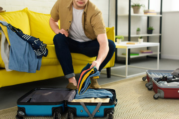 cropped view of young man packing travel bags