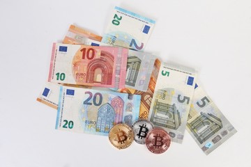 Obraz na płótnie Canvas a heap of different euros with three colorful bitcoins lying in the studio