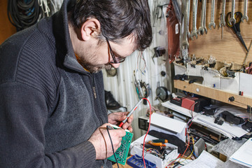 Working in auto workshop / Electrician man is preparing a car alarm system