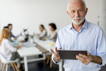 Senior businessman standing with digital tablet in his hand