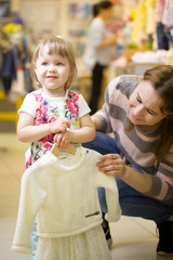Happy little girl with her mother choosing clothes