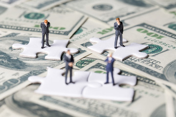 Miniature of investor man stand on jigsaw. Business and Investment concept.