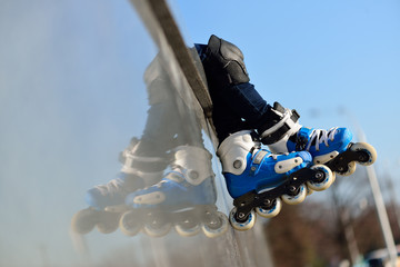 Plakat Feet of group childrens wearing inline roller skates sitting in outdoor skate park, Close up view of wheels befor skating