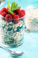 healthy breakfast with natural yogurt, muesli and berries on blue background