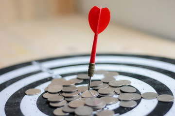 Red dart arrow hit the center target of dartboard and money coin metaphor marketing or saving money...