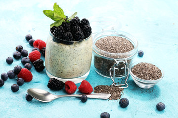 Healthy berry chia pudding in a jar with scattered fruit isolated on rustic grey background