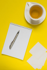 Notepad, pen, tea on a yellow background flat top view with copy space,layout,mocap