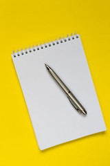 Notepad, pen, on a yellow background flat top view with copy space,layout,mocap