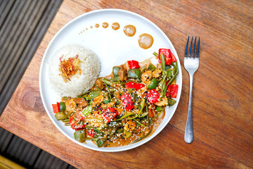 Chicken kung pao on a white plate and on a light wooden table. Chinese food. Food sticks. On the back of a blurry background, a white brick pad is covered with an word love. Top view with copy space