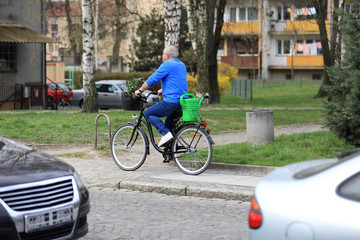 Mężczyzna na rowerze w miejskim parku z sadzonkami i konefką. - obrazy, fototapety, plakaty