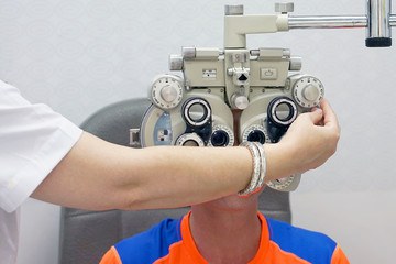 Women ophthalmologist examining patient man with optometrist trial frame. Male patient to check vision in ophthalmological clinic
