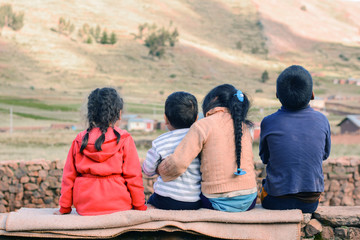 Four latin kids sitting on the wall and admiring a beauty of the nature.