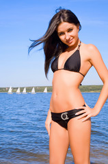 Woman in bikini at river coast