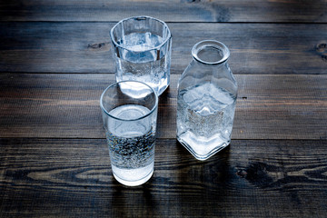 Drinks on the table. Pure water in jar and glasses on dark wooden background space for text