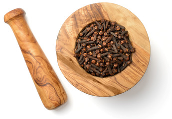 dried cloves in the wooden mortar, isolated on white, top view