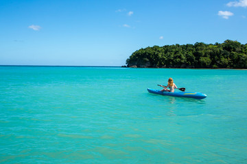 Eine junge Frau paddelt in einem Kajak auf dem Meer in der Karibik auf Jamaika