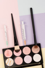 Naklejka premium plastic surgery vs makeup, make-up brushes and syringes on colorful backgrounds