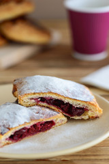 slices of strudel from puff pastry with a cup of tea on a wooden table